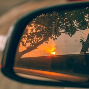 a rear view mirror reflecting a tree and a sunset